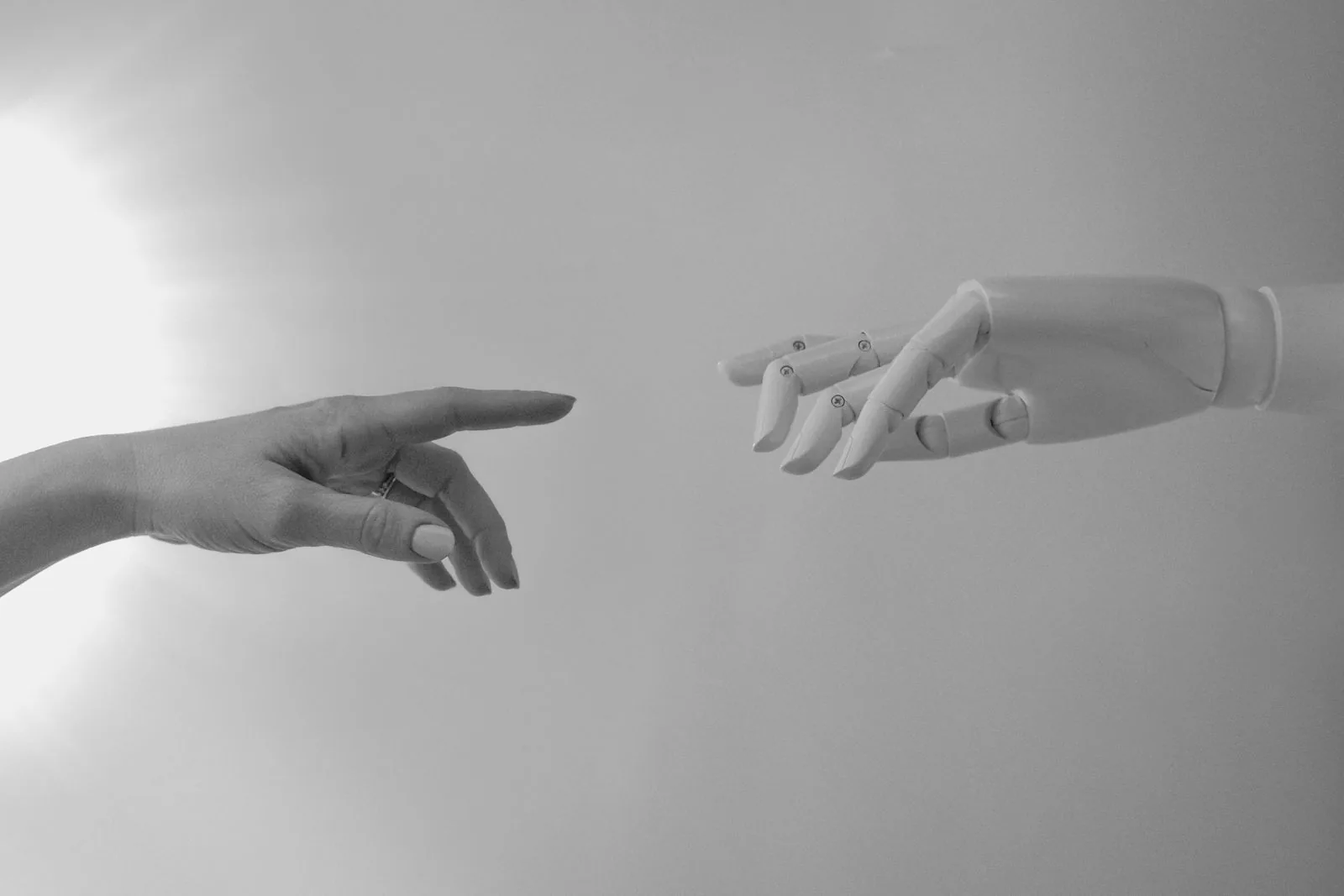 Human hand and robotic hand reaching toward each other, symbolizing AI agents working alongside people