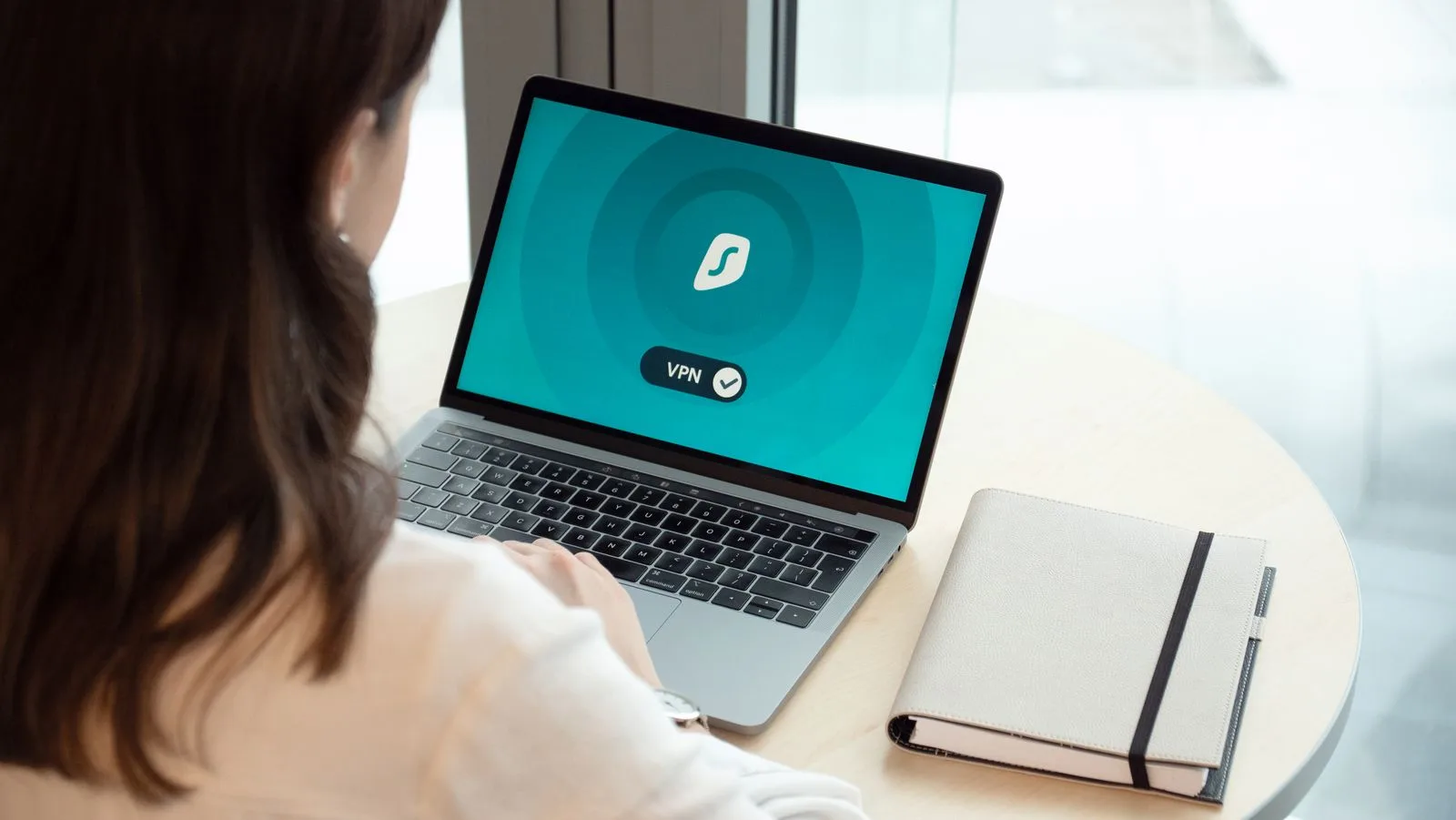 Person using a MacBook showing a secure browsing screen with a checkmark, representing data-access permissions