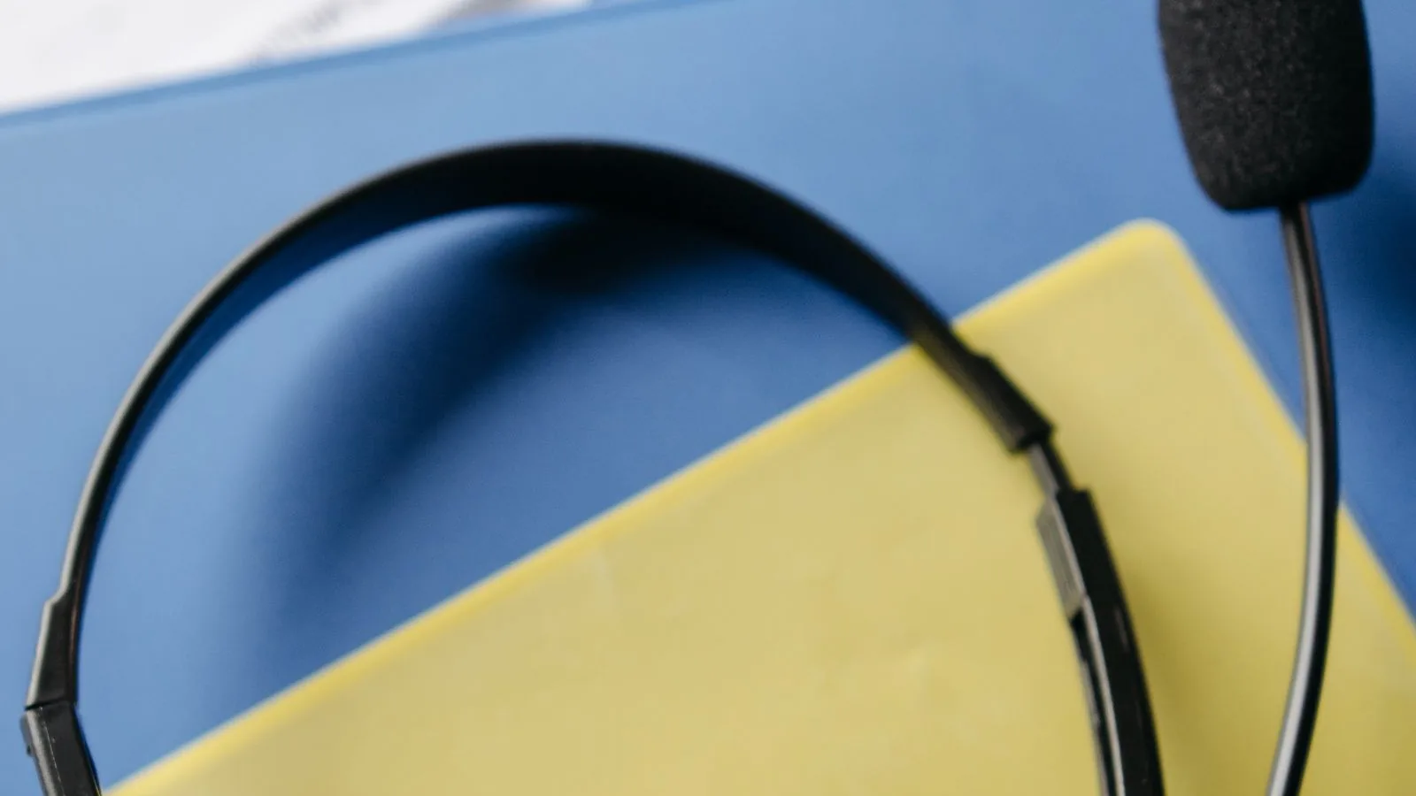 Close-up of a customer-service headset with microphone on blue and yellow folders