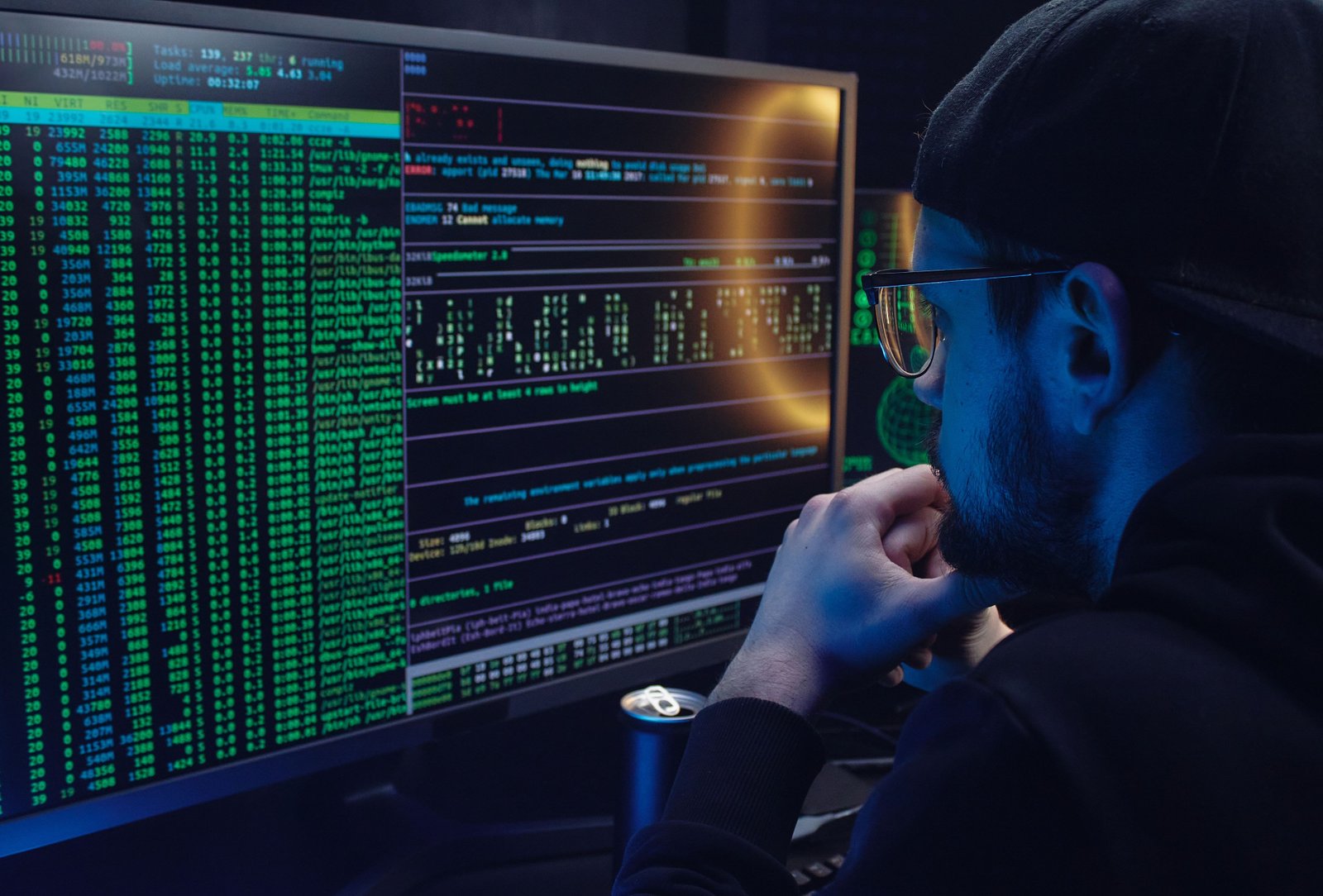 Engineer working at glowing monitors in a dark studio