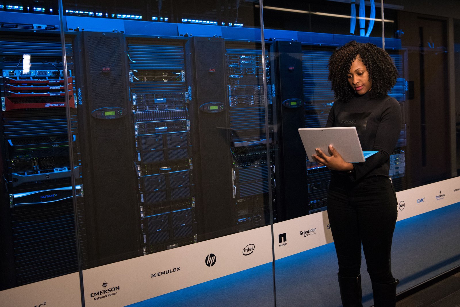 Engineer with a laptop standing beside rows of server racks in a data center
